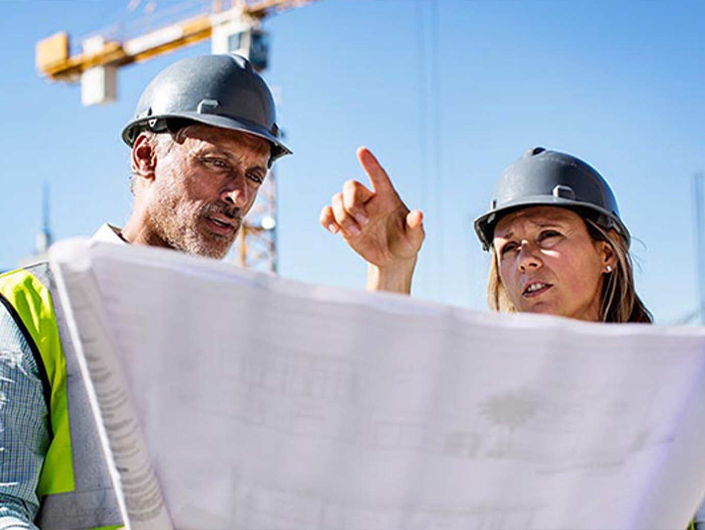 Male and female engineer discussion blueprint on site