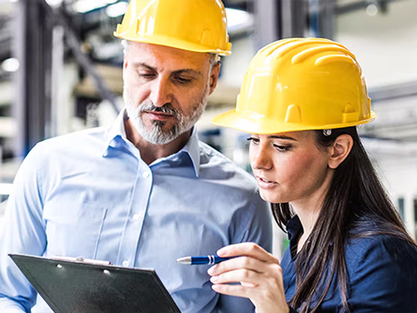 Male and female engineer in safety helmets discussing