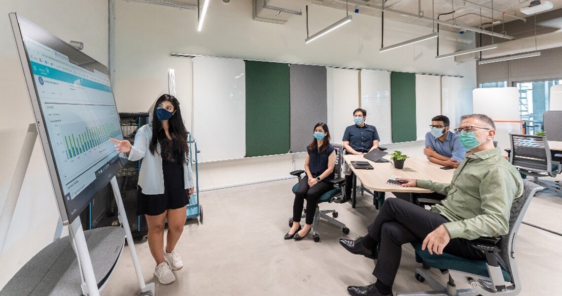 A women employee explaining the team about the graphs in a conference room