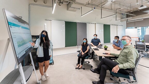 A women employee explaining the team about the graphs in a conference room