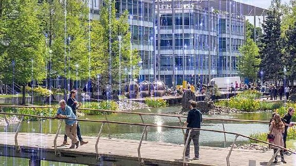 Exterior view of modern corporate buildings across the water body with people casually walking around