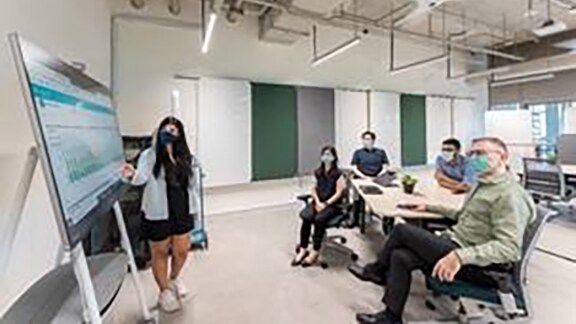 A women employee explaining the team about the graphs in a conference room