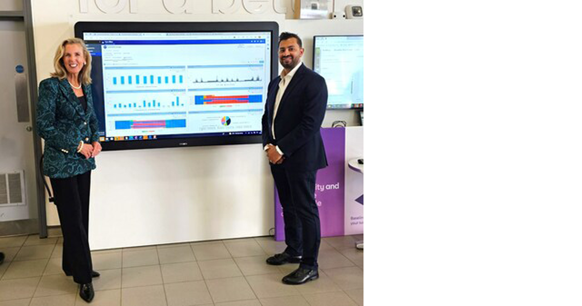 Katie McGinty, Vice President and Chief Sustainability and External Relations Officer at Johnson Controls, alongside an individual from BT, presenting on a large screen displaying charts and data