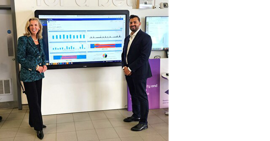 Katie McGinty, Vice President and Chief Sustainability and External Relations Officer at Johnson Controls, alongside an individual from BT, presenting on a large screen displaying charts and data