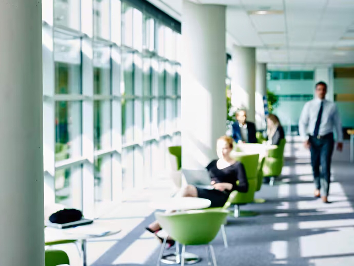 Motion blur images of executive walking in office corridor and few of them sitting and working next to the glass window