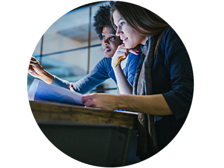 Close-up of two female employees discussing work while looking at the laptop