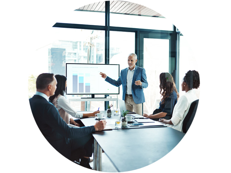 A person giving a presentation to a group of four people in the conference room