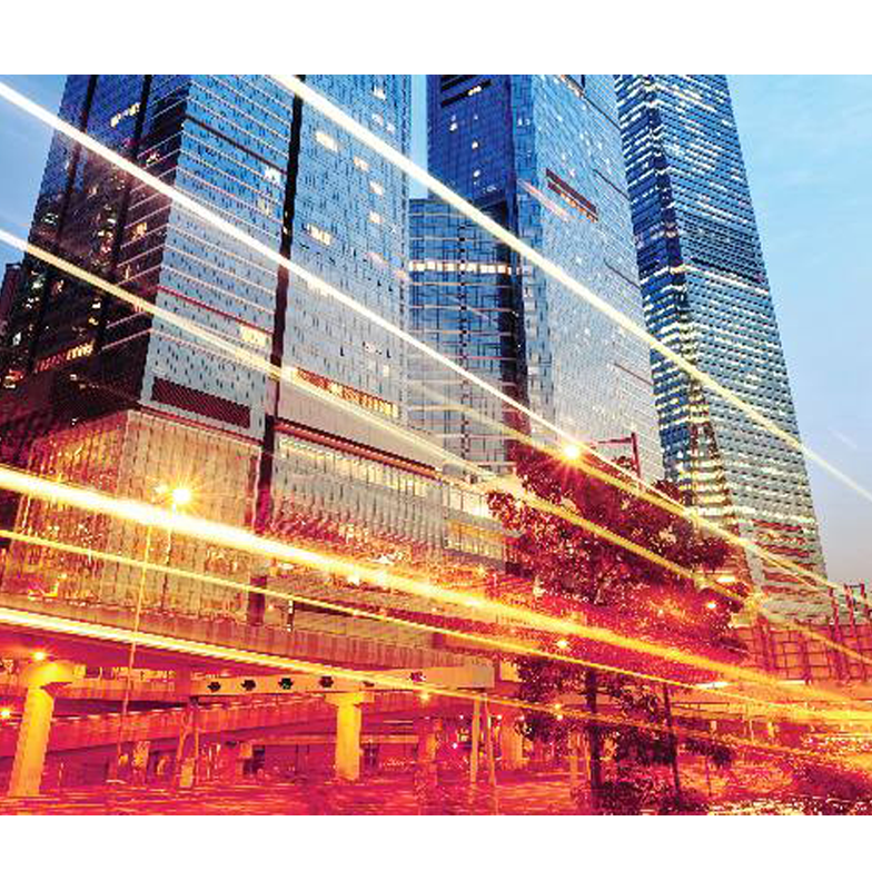 Long-exposure shot of a city at night with light streaks from moving vehicles with tall modern buildings in the background