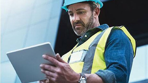 A worker looking at the tab while standing in front of the office