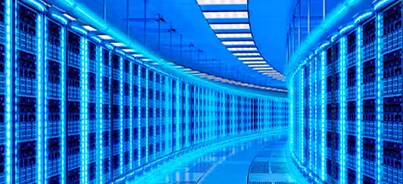 Interior of a data center, characterized by rows of server racks illuminated with blue light
