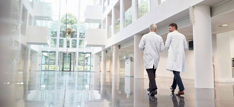 Two medical professionals walking and talking in the modern, brightly lit lobby