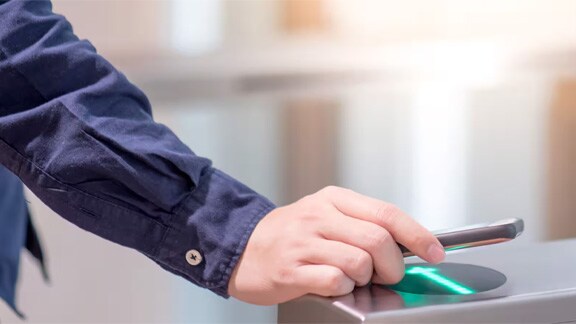 Close-up of a man's hand scanning an identity card at an access control kiosk