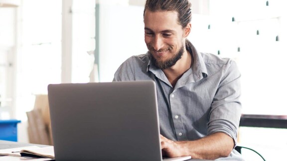 A man smiling and working on his laptop