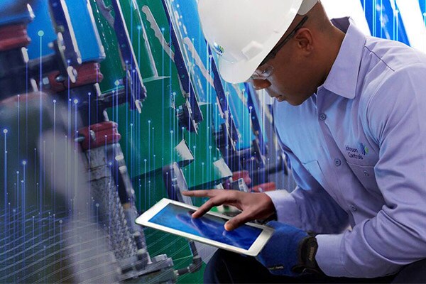 Johnson Controls technician using a tablet and inspecting HVAC equipment