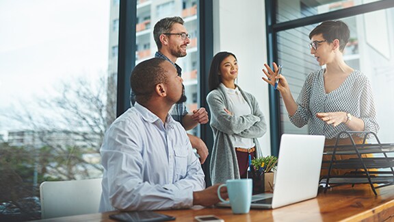 Employees conversing together near a glass window in an office