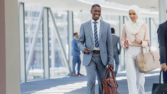 A man and a woman chatting and carrying bags while walking