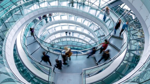 People going down a glass circular stairwell in a building