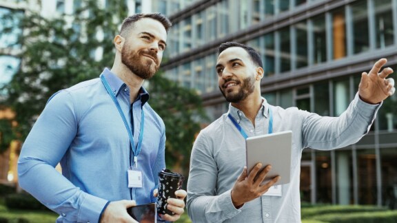 Two men in animated discussion, while one holds a tablet