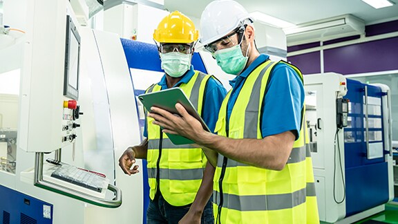 Two factory workers looking at a tablet in a factory