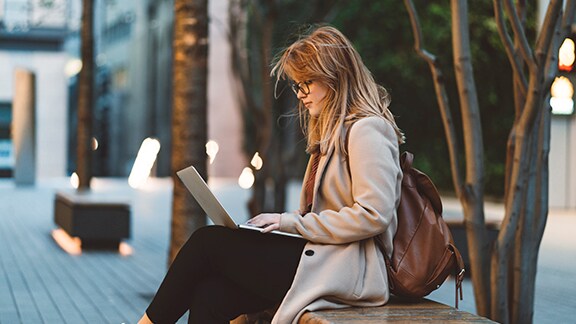 Woman sitting on a bench with a laptop in her lap